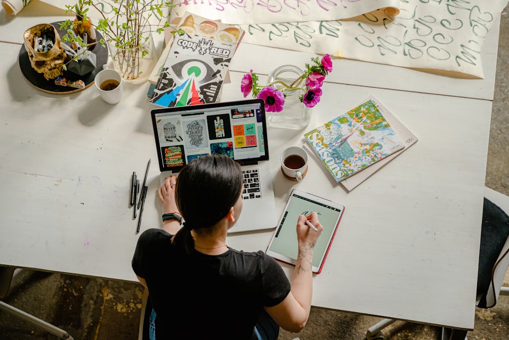 Photo by Antoni Shkraba Artistic workspace featuring calligraphy and digital design on a tablet and laptop.